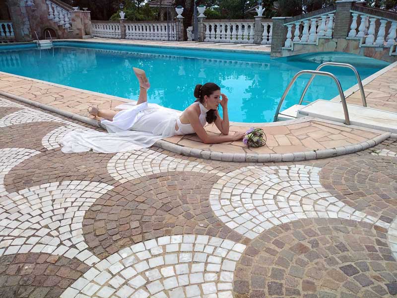 Immagine con modella vestita di bianco vicino una piscina - Fotografie abiti cerimonia ricevimento moda uomo donna. Shooting fotografico vestiti sposa location Villa Fravili